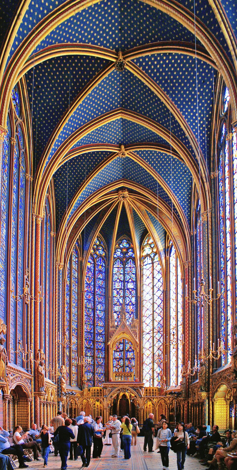 Interior da Sainte-Chapelle em Paris, com paredes altas cobertas de vitrais azuis e vermelhos